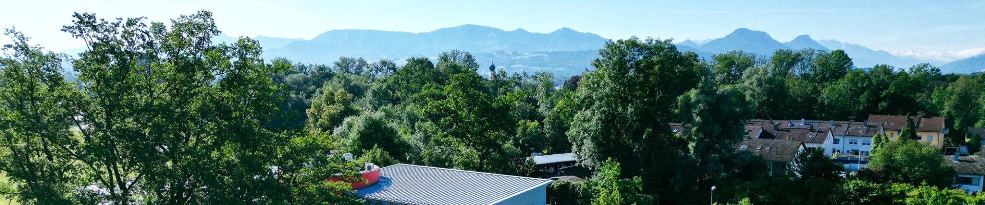 Blick auf das grüne Umland von Rosenheim mit den Alpen im Hintergrund, nahe dem Headquarter der SOCCA GROUP.